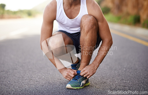 Image of Man, feet and tying laces on road for running, prepare and shoes for cardio or training for marathon. Male person, legs and fitness on mountain street for performance, athlete and ready for exercise