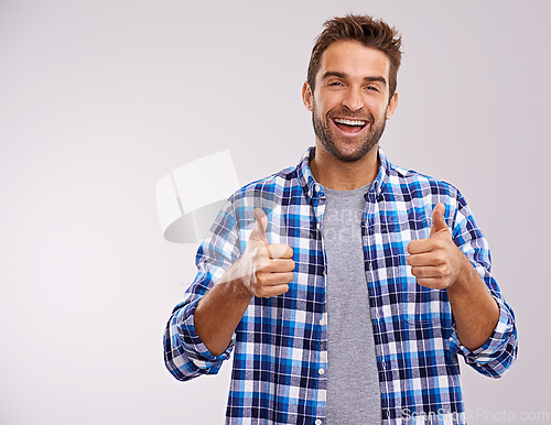 Image of Portrait, excited and man with thumbs up for success, winning or feedback isolated on a gray studio background mockup space. Face, happy person and like hand gesture for emoji, agreement or thank you