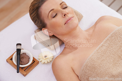 Image of Woman, face and top view for facial at spa, massage and wellness with calm for zen and self care. Cosmetics, beauty and brush with paste for mask, relax and peace at luxury resort with treatment