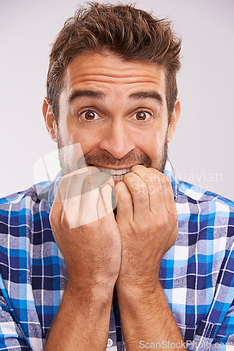 Image of Nervous, portrait and man with nail bite for anxiety, fear and funny stress gesture in a studio. Worried, scared and male person with hands to face for comedy with grey background and modern style