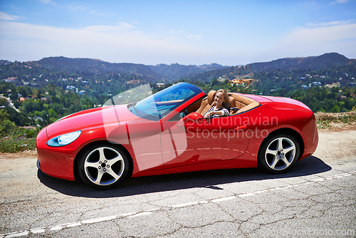 Image of Convertible, car and woman on a drive in city, outdoor in summer with happiness on road trip. Luxury, transport and portrait of female driver to travel on highway hill with red vehicle on street