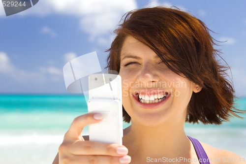 Image of happy woman with phone on the beach