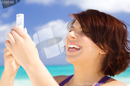 Image of happy woman with phone on the beach