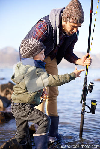 Image of Father, fishing and teaching for young boy, rocks and bonding for activity by ocean. Sea, rod and learning how to fish for childhood development, winter and hobby together while on seaside vacation