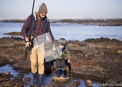 Image of Man, kid and fishing at sea in winter as hobby with bonding for child development, growth and life skills in Australia. Dad, boy and stand in boulders at coast for family tradition, memory and care