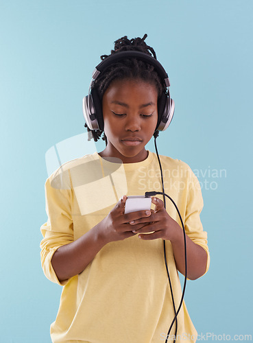 Image of Phone, music and black boy with headphones in studio for internet, playlist or search on blue background. Smartphone, radio and teen model with app for podcast, streaming or sign up subscription