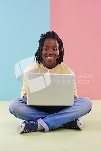 Image of Teenager, portrait and laptop in studio for online education, e learning and creativity on the floor. Kid, student or African boy with computer for school in pastel color or blue and pink background