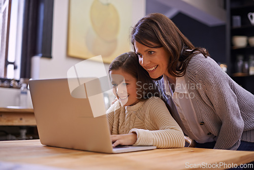 Image of Mama, child and learning with laptop for support, care or browsing in the kitchen at home. Mother, daughter or kid typing on computer for social media, reading or helping girl on project or homework