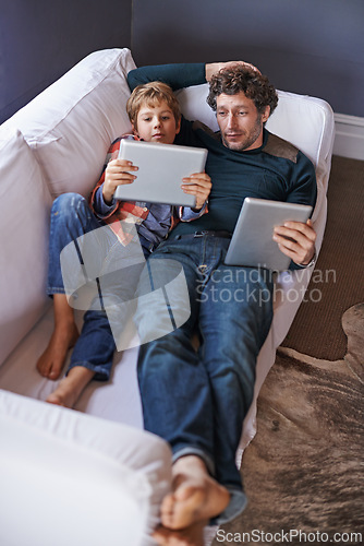 Image of Father, son and tablet for gaming on sofa together, technology and online streaming for bonding at home. Digital world, internet and man with boy child in living room, gamer app and entertainment