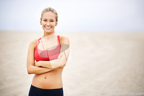 Image of Woman, portrait and fitness on beach sand with arms crossed, confident and smile with wellness and outdoor. Exercise, athlete and sports with happiness for health, marathon or race for cardio workout