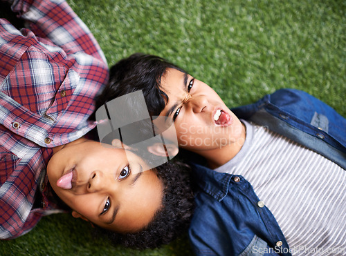 Image of Siblings, girl and boy on grass, funny and portrait for smile, tongue out or relax in backyard at family home. Crazy children, brother and sister for care, comic or above on vacation, lawn and spring