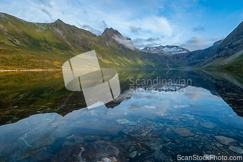 Image of Pristine mountain lake reflecting majestic peaks in serene morni