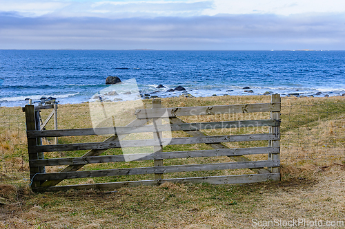 Image of Weathered wooden fence overlooking rocky shoreline on cloudy day