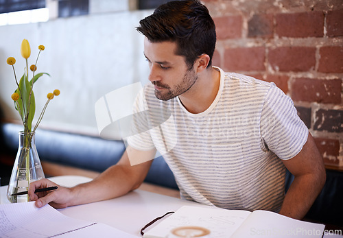 Image of Young man, paperwork and coffee shop with documents for planning, reading or finance at indoor restaurant. Male person or freelancer checking financial budget, journal or planner in notebook at cafe