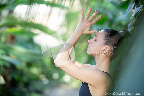 Image of Female meditating and practicing yoga in tropical rainforest. Beautiful young woman practicing yoga outdoor with tropical forest in background.