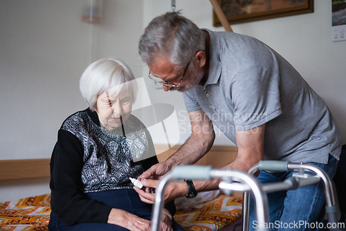 Image of Man is helping an elderly woman with everyday tasks, helping with technology, setting video face time with her family using smart phone.