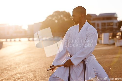 Image of Serious man, karate and fitness with nunchuck in city for kata, fighting technique or style. Young male person or muay thai fighter with weapon for martial arts or self defense on street in town