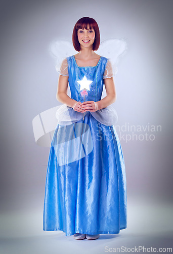 Image of Woman, fairy godmother and smile in studio portrait with wand, wings and dress for magic by background. Person, fantasy and star with glow, shine and happy with power, wish and surreal fairytale