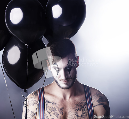 Image of Man, circus and topless for theatre performance on dark background with light for stage, creative and entertainment. Portrait, mime and performer with balloons, face paint and tattoo for creativity