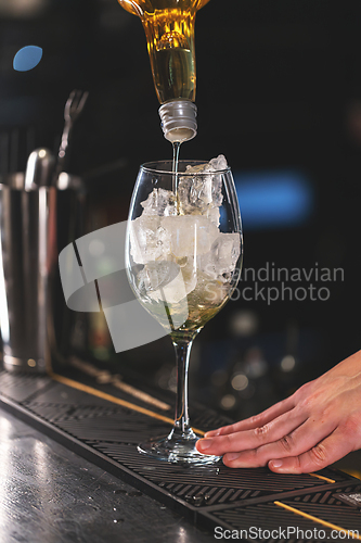 Image of Bartender pouring a golden liquid into a glass