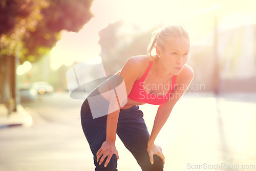 Image of Tired woman, rest and fitness with break in city after workout, running or cardio exercise. Exhausted or determined female person or athlete in recovery, training or breathing from run in urban town