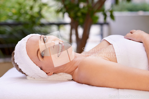 Image of Happy woman, portrait and relax with towel for spa, zen or massage table at hotel or outdoor resort. Face of female person with smile, enjoying facial or body treatment at accommodation for wellness