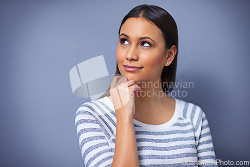 Image of Woman, thinking and smile for idea in studio, planning and happy for solution on blue background. Female person, brainstorming and contemplating a choice or decision, ponder and small business owner