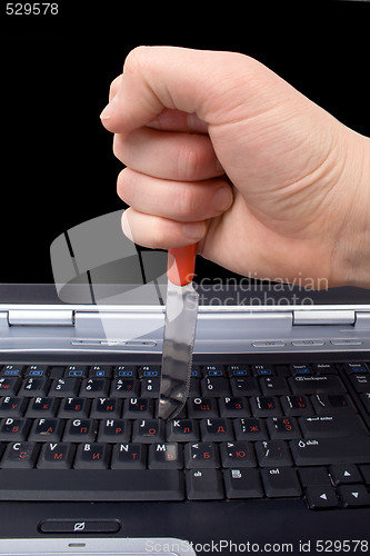 Image of Hand with a knife in the laptop keyboard