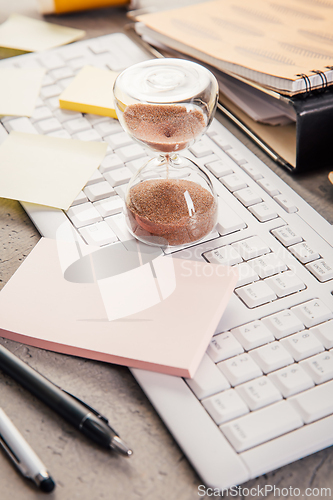 Image of Crop of hourglass on home office table count measure time.  Workplace of busy employee, time management and burnout concept
