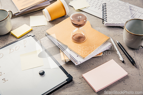 Image of Crop of hourglass on home office table count measure time.  Workplace of busy employee, time management and burnout concept