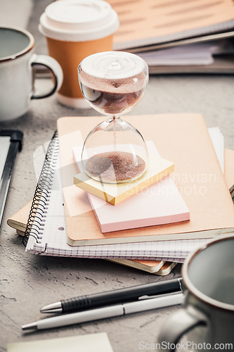 Image of Crop of hourglass on home office table count measure time.  Workplace of busy employee, time management and burnout concept