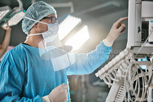 Image of Surgery, machine and doctor with monitor in hospital for healthcare, theatre operation or analysis. Medical, man and surgeon in scrubs with digital technology for cardiology, procedure or information