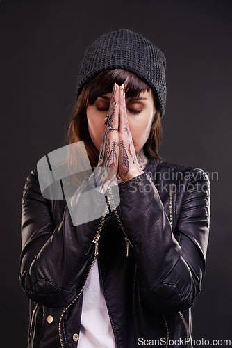 Image of Praying, tattoo or woman in studio for fashion in leather jacket on black background for edgy style. Forgive, hope or cool female punk model with ink for unique art, aesthetic or creative expression