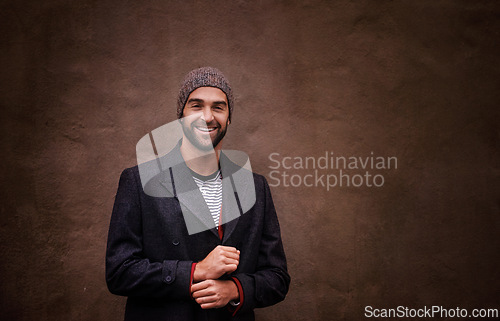 Image of Man, portrait and smile with urban, fashion and trendy gentleman jacket. Model, winter and beanie with city, happiness and outdoor positivity for cool hipster style isolated on brown wall background