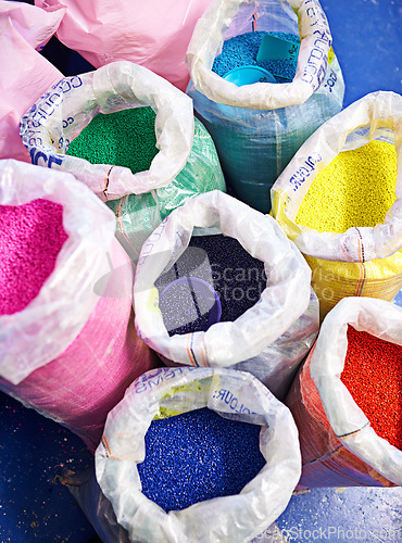Image of Bag, color and plastic resin with recycling for dye, manufacturing or ecology on floor in factory. PVC pellets, industry and molecule for polymer at plant for storage, particle and above in warehouse