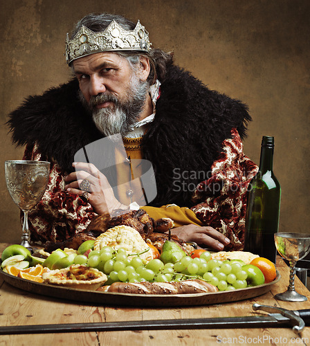 Image of King, confident and feast in table with wine as royalty on dining hall for tradition, culture and meal in palace. Portrait, monarch and leader with eating buffet or supper with sword for chicken