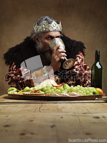 Image of King, feast and drink wine in table as royalty on dining hall for tradition, culture and meal in palace. Portrait, monarch and leader with eating buffet or supper with chicken in confidence and crown