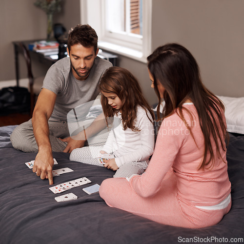 Image of Parents, girl and playing cards to relax for fun with bonding, learning and games with strategy in home bedroom. Father, mother and daughter on bed, maths and teaching with connection in family house