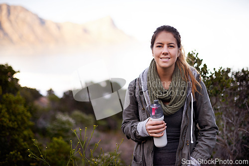 Image of Woman, hiking and portrait in nature with bottle for water with fitness, hydration or smile on adventure. Girl, person and trekking in bush, mountains and rocks for journey on vacation in Cape Town