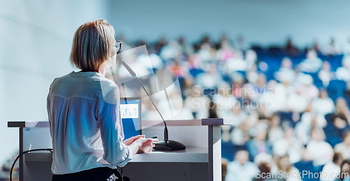 Image of Female speaker giving a talk on corporate business conference. Unrecognizable people in audience at conference hall. Business and Entrepreneurship event.