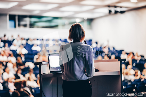 Image of Female speaker giving a talk on corporate business conference. Unrecognizable people in audience at conference hall. Business and Entrepreneurship event.
