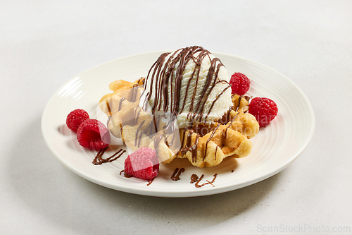 Image of belgian waffle decorated with melted chocolate sauce and ice cre