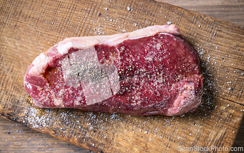 Image of fresh raw beef steak meat with salt and pepper on wooden cutting