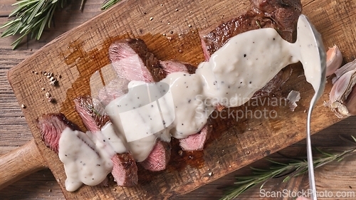 Image of Chef pours pepper sauce on a slices of freshly grilled beef stea