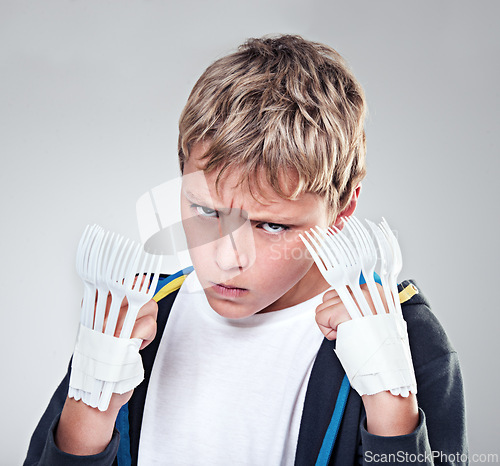 Image of Portrait, angry and boy with fist, fight and expression with frustrated on grey studio background. Face, model and kid with forks for claws and reaction with costume and aggressive with rage or child