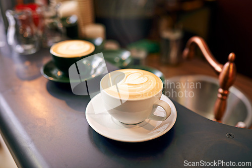 Image of Coffee on table, cup and latte with art for creativity, cappuccino or caffeine drink with pattern. Warm beverage on counter, foam and milk with heart or leaf design, hospitality and service at cafe