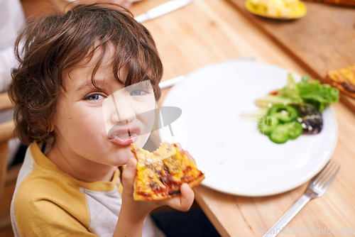 Image of Boy, child and pizza in portrait at dinner table for eating, food and relax on holiday in family house. Kid, happy and playful in dining room for lunch with nutrition, diet and home for funny face