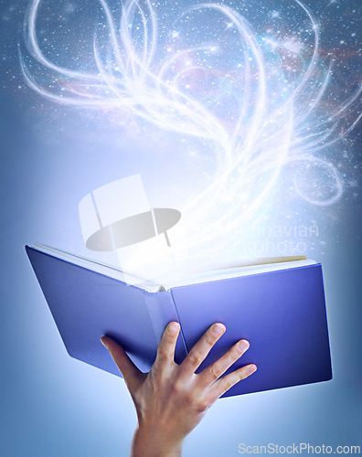 Image of Hand, person and magic with book, fantasy and sparkle with education on a blue studio background. Model, closeup and reader with literature and knowledge with learning and creativity with glitter