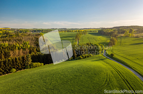 Image of Drone flies over countryside with green field.