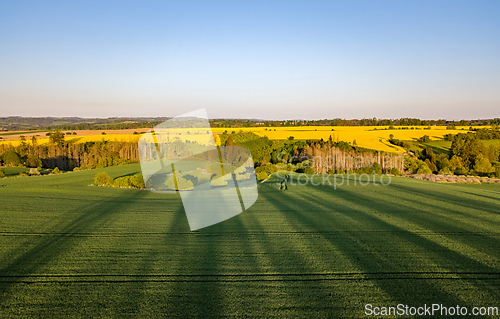 Image of Drone flies over countryside with green field.